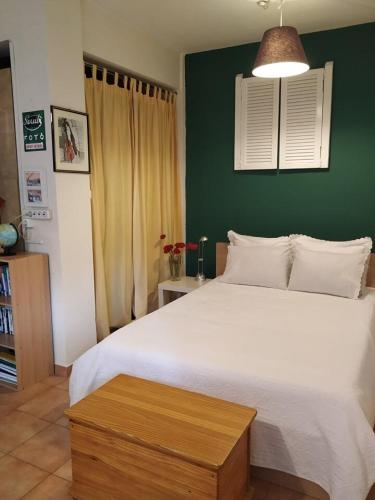 a bedroom with a white bed and a green wall at Art & Books Guesthouse Alexandroupoli in Alexandroupoli
