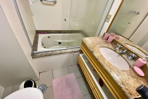 a bathroom with a sink and a mirror and a tub at Piscina, Brinquedoteca e Lazer completo in Guarujá