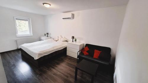 a white bedroom with a bed and a chair at The Other House, Piliscsaba in Piliscsaba