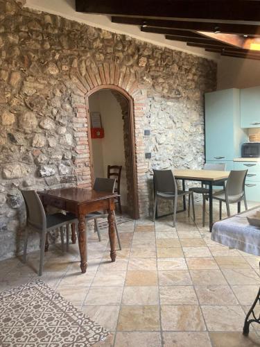 a room with tables and chairs and a stone wall at Rustico di Benellini Angela in Polpenazze del Garda
