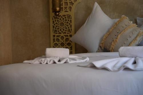 a white bed with a candle and towels on it at Suite Oasis - cosy et moderne in Marrakech