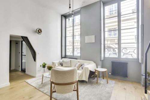 un salon avec un canapé et deux fenêtres dans l'établissement Reve du Marais, à Paris