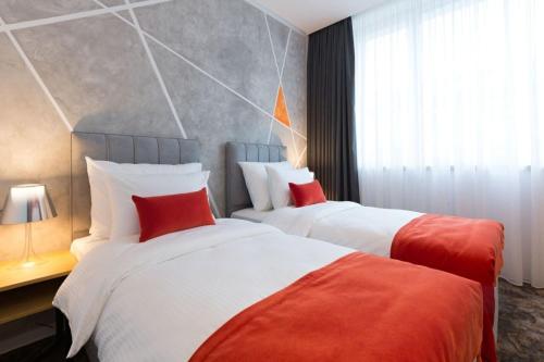 VăleniにあるRoyal Inspira Hotel Boutiqueの赤い枕が置かれたホテルの部屋にはベッドが2つある