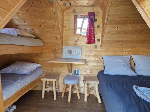 Cette cabine comprend 2 lits et une table. dans l'établissement La cabane enchantée, Logement Insolite à La Ferme, à Le Vernet