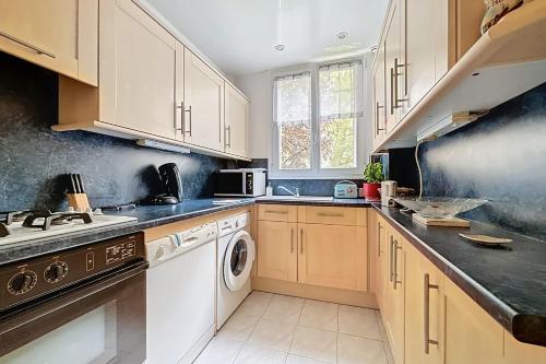La cuisine est équipée de placards blancs et d'un lave-vaisselle. dans l'établissement Spacious 2-room apartment near Nation, à Paris