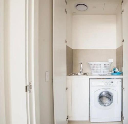 a laundry room with a washing machine and a sink at Sky-High Luxury Retreat with Breathtaking View in Sydney