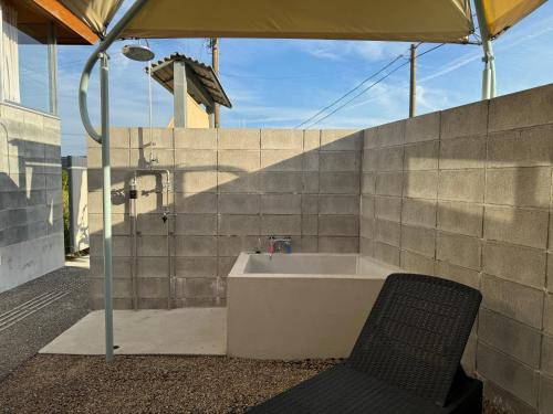 a bathroom with a tub and a chair under an umbrella at Villa by the sea ドットナンバー in Amino
