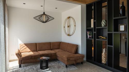 a living room with a brown couch and a chandelier at steiRerBLiCke - Domaine Sernau Muscat in Gamlitz