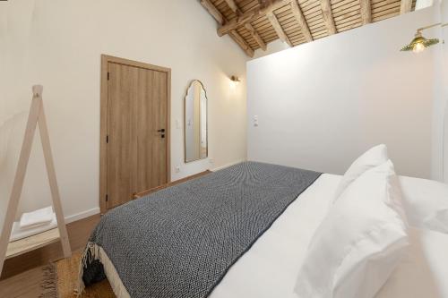 a bedroom with a bed with white sheets and a mirror at Casa da Rosalina in Marvão