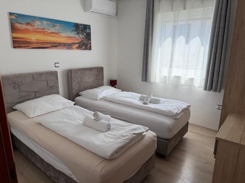 two beds in a room with a window at Apartments Puntamika in Zadar