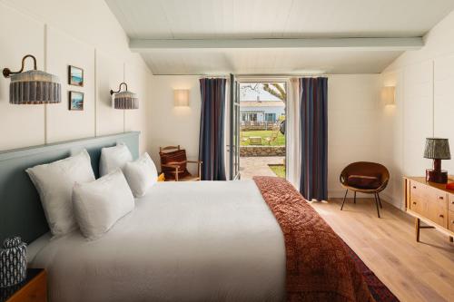 a bedroom with a large white bed and a window at La Mission Hôtel & SPA - l'île d'Yeu in L'Ile d'Yeu