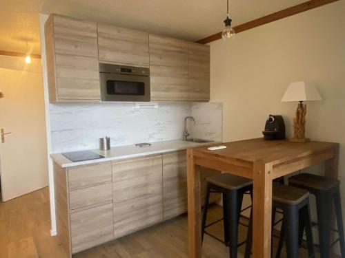 - une cuisine avec une table en bois et un évier dans l'établissement Appartement 4 pers, balcon sud, quartier Passeaux - Alpe d'Huez - FR-1-405-111, à L'Alpe-d'Huez