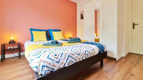 une chambre avec un lit avec des oreillers bleus et jaunes dans l'établissement Cocon Design & Confortable - Parking - RBNB, à Colmar