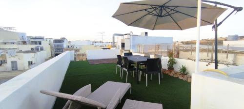 a balcony with a table and chairs and an umbrella at Charming Townhouse - Steps from Waterfront in Marsaxlokk