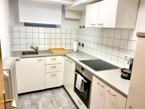 a kitchen with white cabinets and a sink at Bodensee Bungalow in Immenstaad am Bodensee