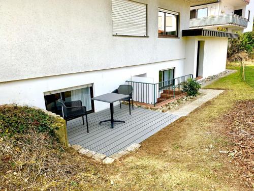 a deck with a table and chairs in front of a house at Bodensee Bungalow in Immenstaad am Bodensee