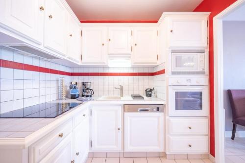 - une cuisine blanche avec des placards blancs et du carrelage rouge dans l'établissement La Rochelle en famille - 5 personnes, à La Rochelle