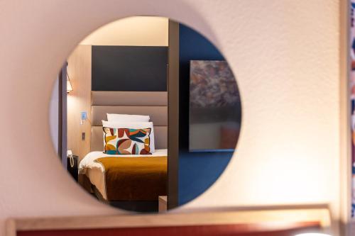 a hotel room with a bed and a mirror at Mercure Grenoble Centre Porte des Alpes in Grenoble