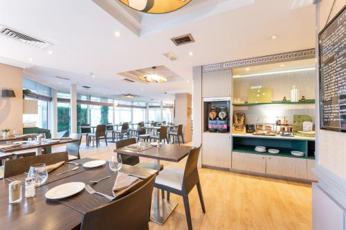 a restaurant with tables and chairs and a kitchen at Mercure Grenoble Centre Porte des Alpes in Grenoble