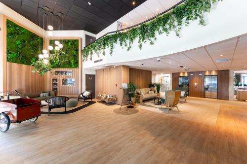 a large lobby with furniture and plants on the ceilings at Mercure Grenoble Centre Porte des Alpes in Grenoble