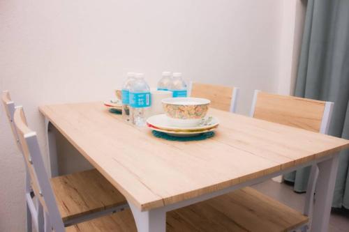 a wooden table with a bowl and plates on it at Hana Homestay in Tawau
