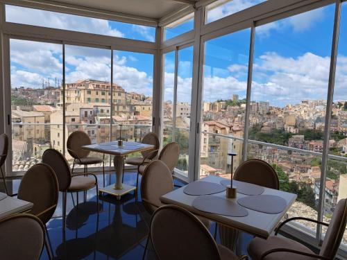 a restaurant with tables and chairs and large windows at Hotel Sicilia in Enna