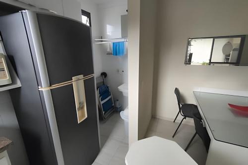 a small kitchen with a refrigerator and a table at Riviera Dreams: Piscina, Sauna e muito mais! in Bertioga