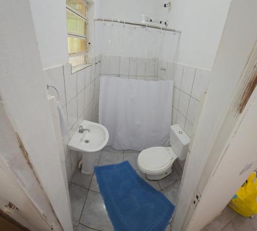a white bathroom with a toilet and a sink at Refúgio do Coração in Bueno Brandão