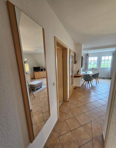 a living room with a large mirror and a kitchen at Pferdekoppel-im-Haus-zwischen-den-Wassern in Behrensdorf