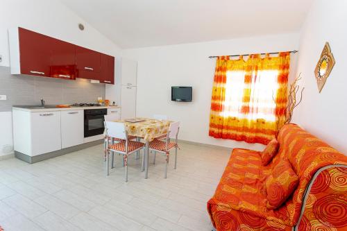 a kitchen and a living room with a couch and a table at Villanna - Villa con piscina & splendido giardino in Alimini