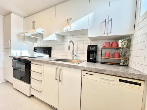 a kitchen with white cabinets and a sink at 4 Grandes Chambres Centre-Ville in Quebec City