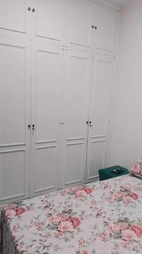 a bedroom with white cabinets and a bed with a floral blanket at Spectacular Agriões Location in Teresópolis