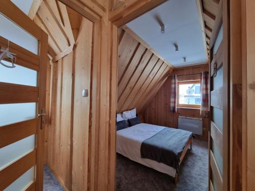 een slaapkamer met een bed in een houten hut bij Podhalańska Chatka Zakopane in Zakopane