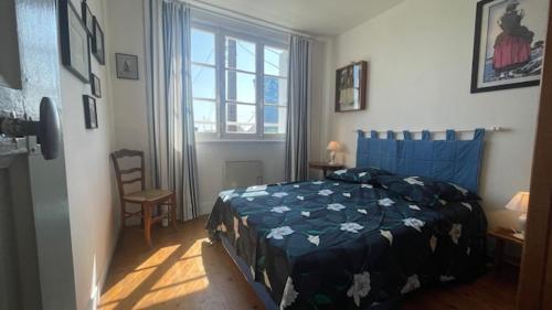 une chambre avec un lit avec une couette bleue et une fenêtre dans l'établissement Ty Prévosto - jardin clos - plage à pieds, à Camaret-sur-Mer