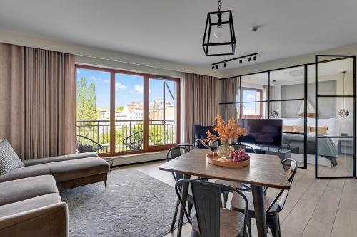 a living room with a table and a living room with a view at Waterlane Island - Riverview Pool, SPA, Gym & Parking by Downtown Apartments in Gdańsk
