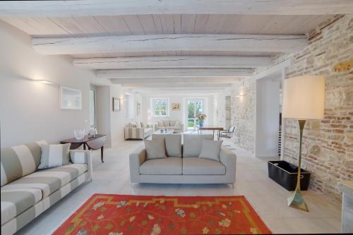 a living room with white furniture and a brick wall at Agromarino in Sirolo
