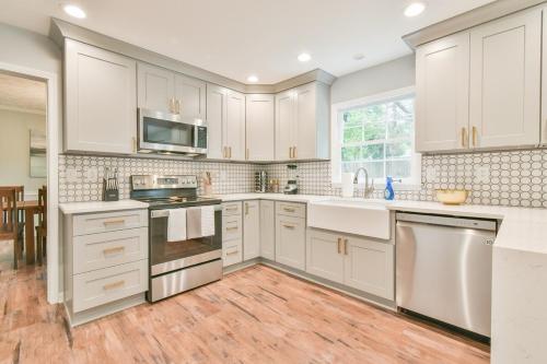 a kitchen with white cabinets and a wooden floor at Cozy Home with Arcade, Ping Pong & Fenced Backyard in Lawrenceville