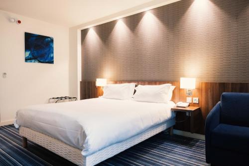 a hotel room with a large bed and a blue chair at Holiday Inn Express Lille Centre by IHG in Lille