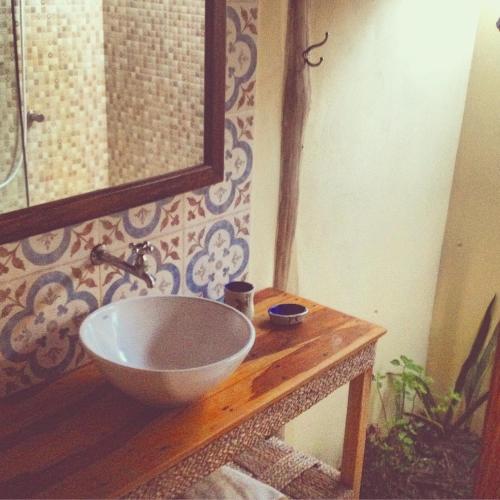 a bathroom with a bowl sink on a wooden table at Caju Bangalôs in Ponta do Anel