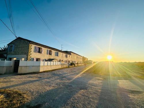 an empty road with the sun setting in the distance at Les Appartements du Mas - Aventurine in Aigues-Mortes