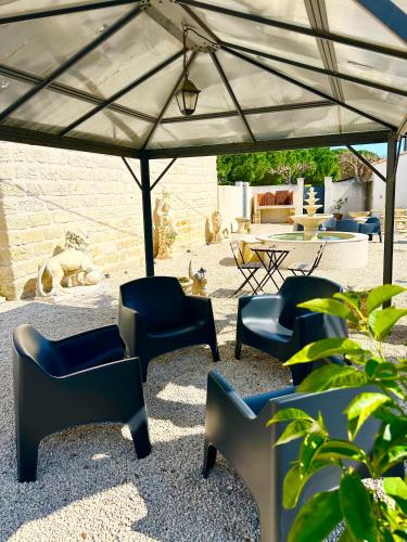 a group of chairs under a large umbrella at Les Appartements du Mas - Aventurine in Aigues-Mortes