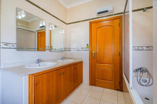 ein Badezimmer mit zwei Waschbecken und einer Holztür in der Unterkunft Filomena Golf Paradise in Guia