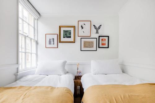 two beds in a white room with pictures on the wall at Central Georgian Townhouse with Free Parking in Bath