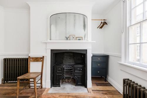 a room with a fireplace with a mirror and a chair at Central Georgian Townhouse with Free Parking in Bath