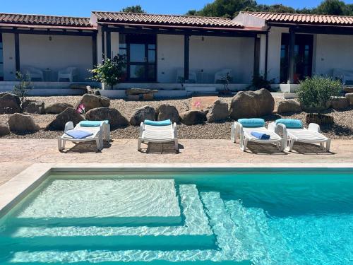 una piscina con sedie e sedie accanto a una casa di Agriturismo Nuraghe Tuttusoni a Aglientu