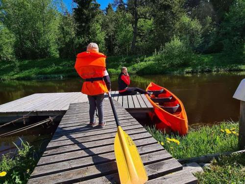 a person standing on a dock with a paddle and a boat at Kassioru Puhkemaja in Kiidjärve