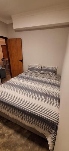 a bedroom with a bed with striped sheets at Casa Fundo de Quintal in Baía Formosa