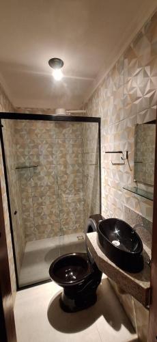 a bathroom with a black toilet and a shower at Casa Fundo de Quintal in Baía Formosa