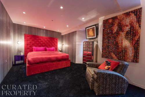 a bedroom with a red bed and a chair at Amazingly Luxurious Loft Apartment, Soho - 3 Bedrooms, 2 Bath & Office in London