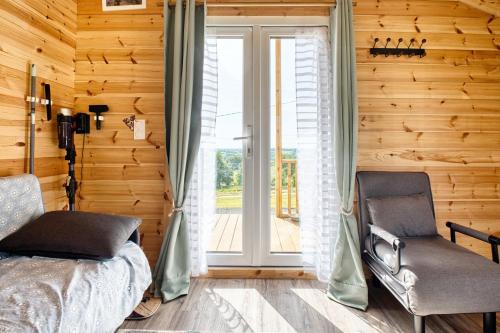 a bedroom with a bed and a chair and a window at Chalet de campagne en Dordogne in Thénac